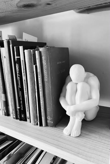 Escultura contemplativa junto a libros de psicoanálisis